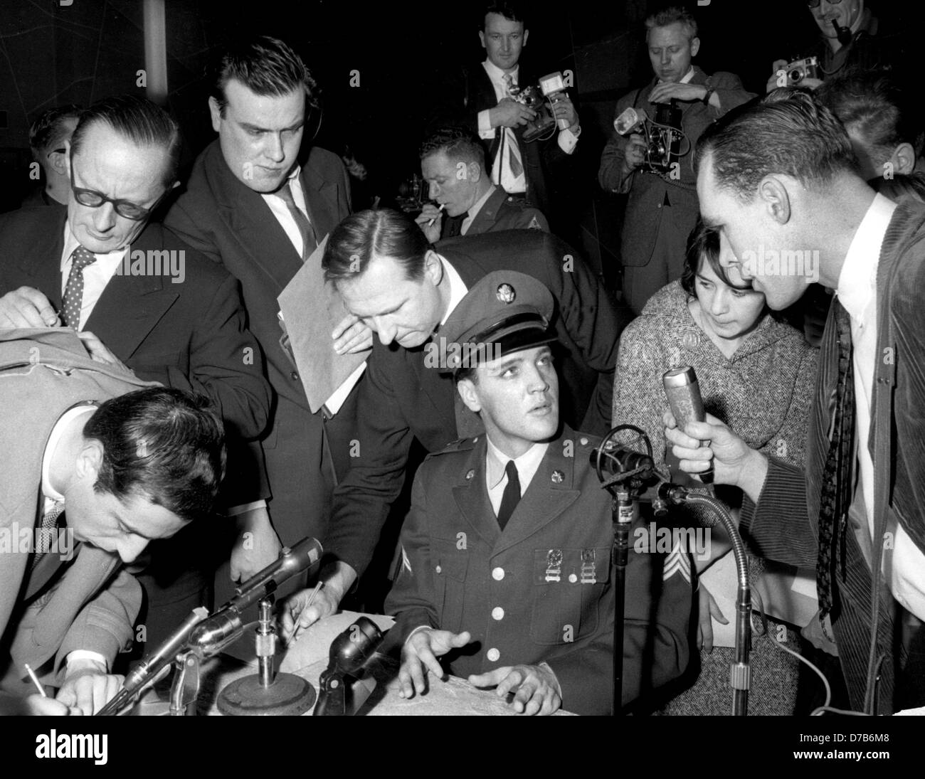 American teenager idol Elvis Presley (in uniform) is surrounded by ...