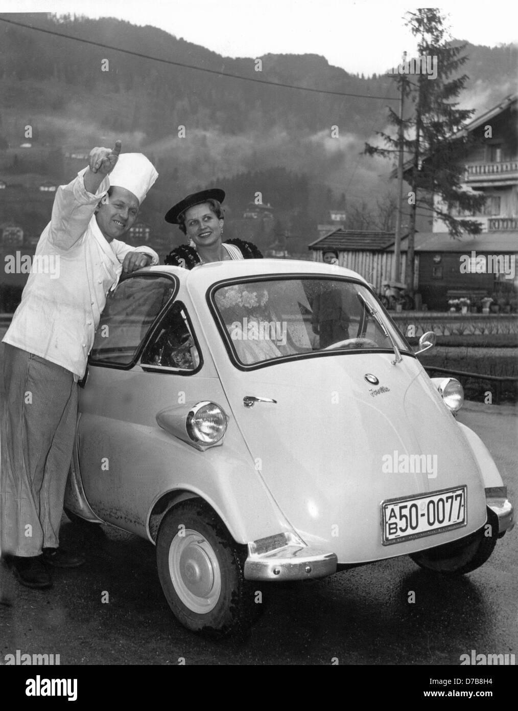 A chef shows a driver in a BMW Isetta the way. The Bavarian engine works have built an engine coupé called 'Isetta'. Stock Photo