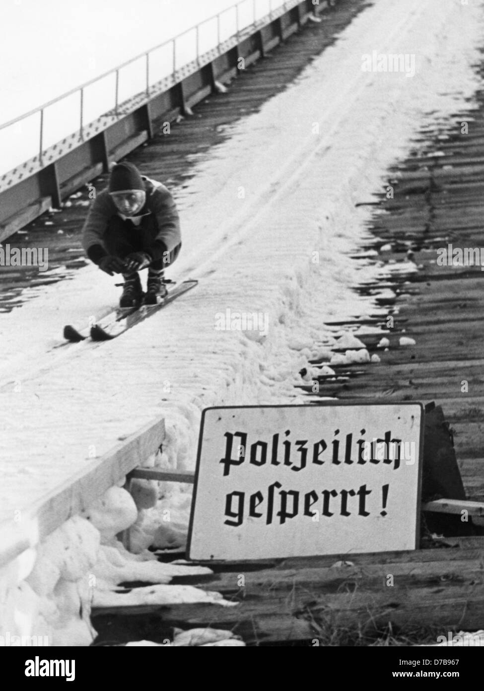 Despite the sign saying "Closed by the police", Max Bolkart sets for his jump of eighty metres on the "Grosse Olympiaschanze" in Garmisch-Partenkirchen at the traditional New Years tournament in 1957. The police ban certainly did not affect the professionals. Stock Photo