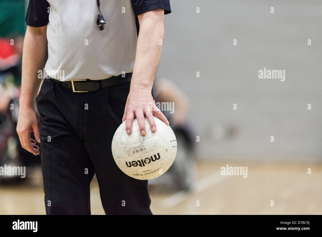Referee holding volley ball in hand, whistle around neck, tight cropped