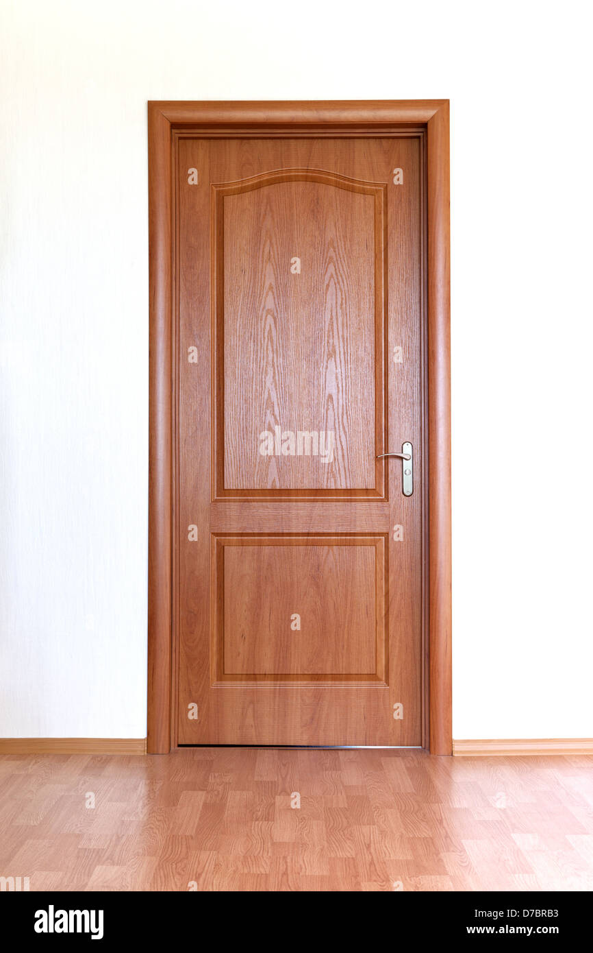 Closed brown wooden door in white wall Stock Photo