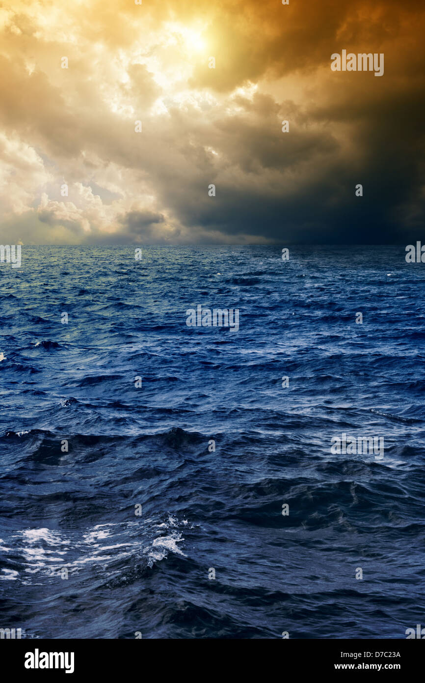 Stormy deep blue sea, dark sky, sun shines through clouds Stock Photo ...