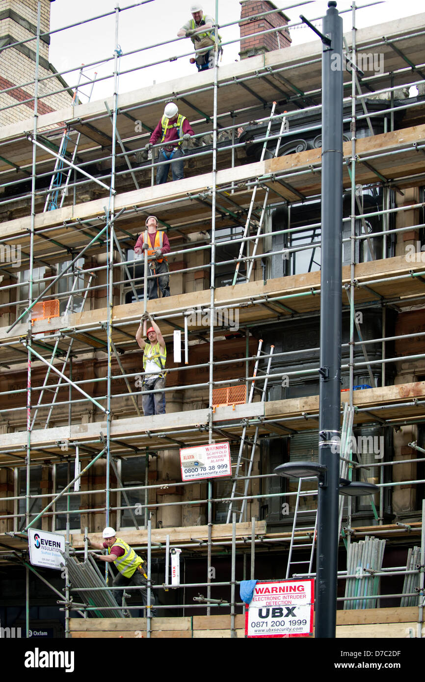 Builders on St Mary Street in Cardiff use levels of scaffolding to pass pipes to the top of the