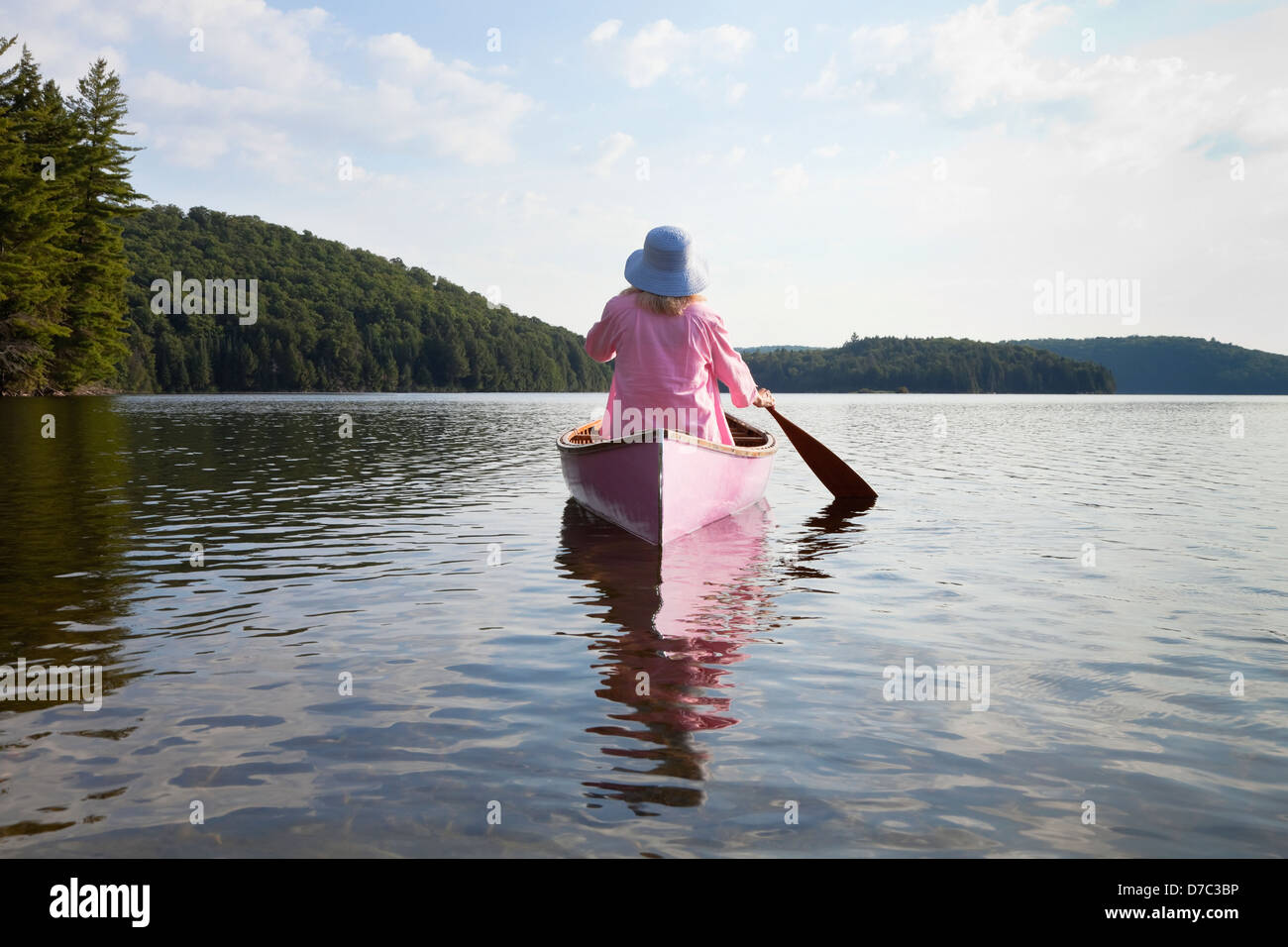 Senior Woman Dressed In Pink And Paddling Her Pink Canoe On Lake In