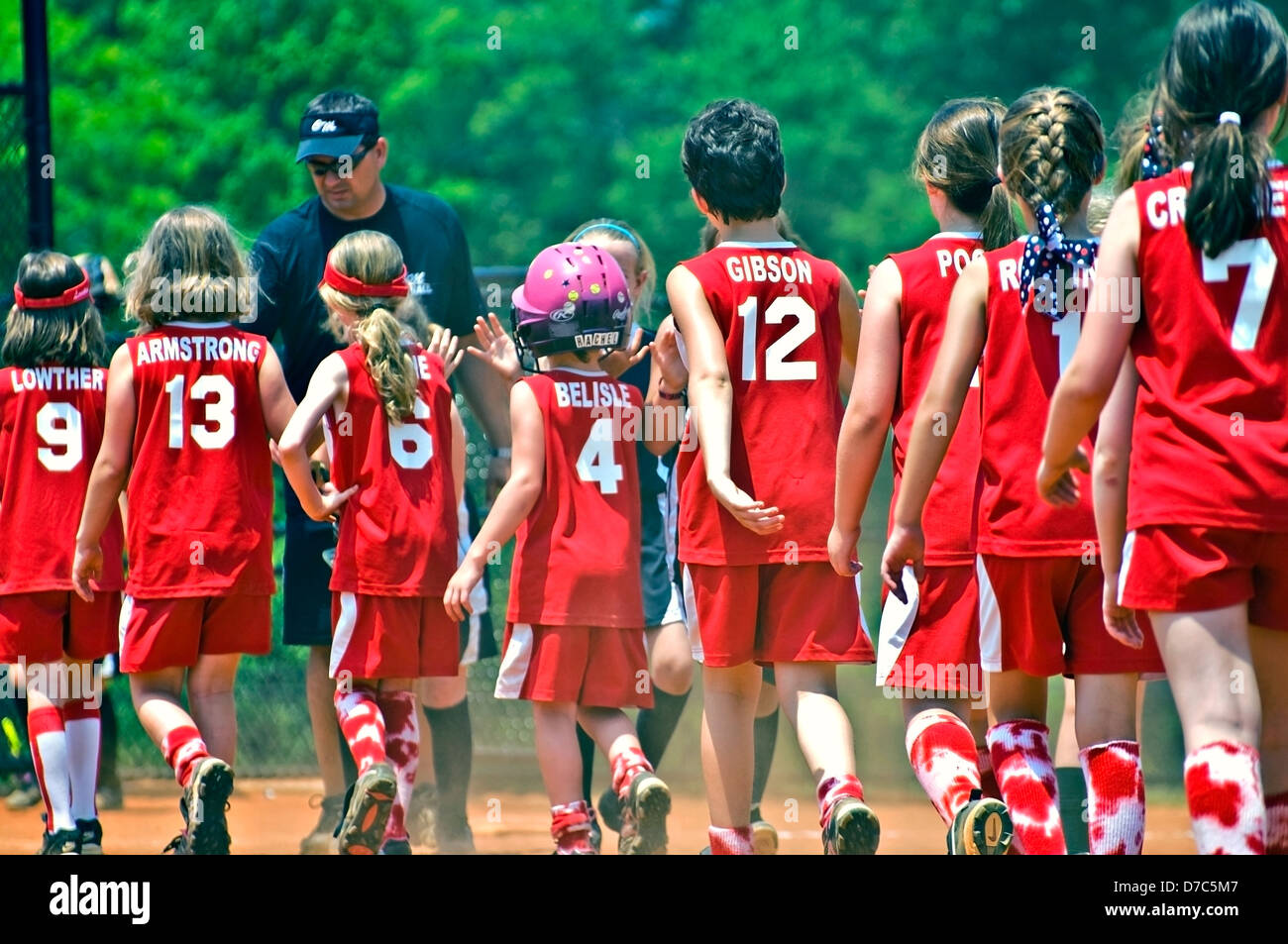 Young girls and coach at the end of a softball game giving