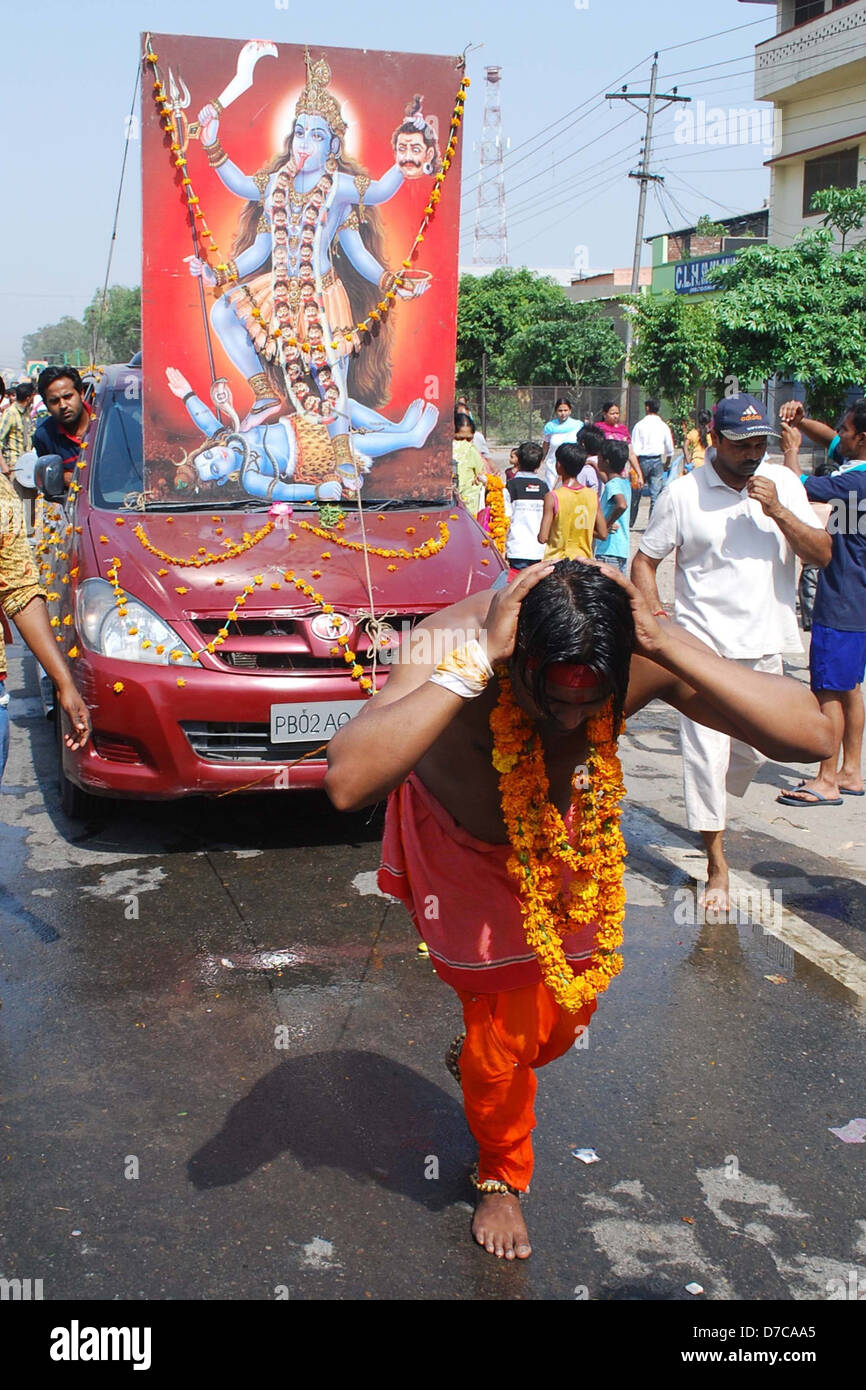 A Hindu devotee pulls a car with ropes, attached to hooks, piercing his back, as he takes part in a religious procession Stock Photo