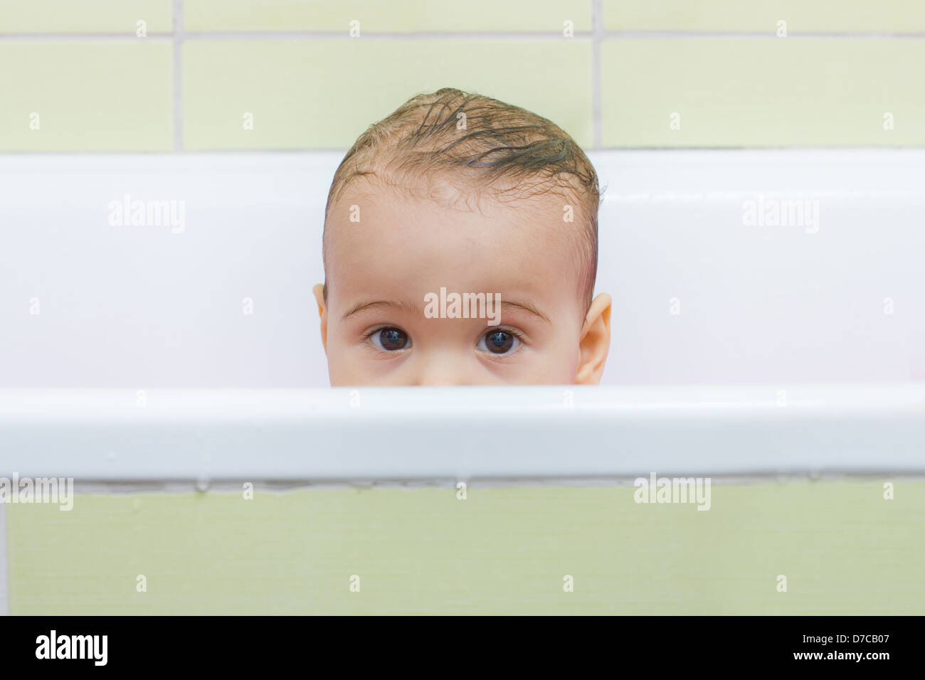 Baby peeking out of the tub while bathing Stock Photo Alamy