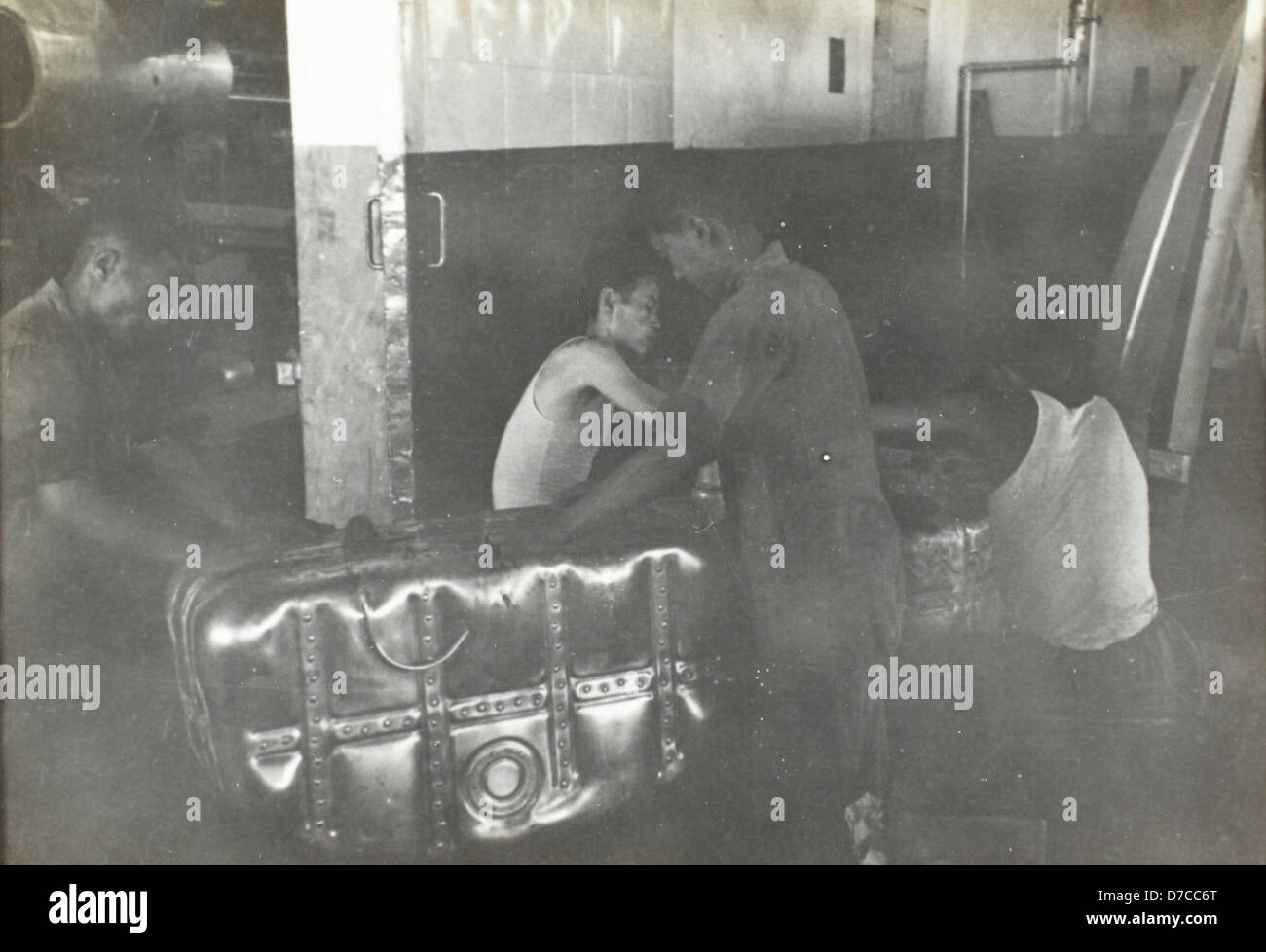 This image shows workers handling a fuel tank, likely in an aerospace ...