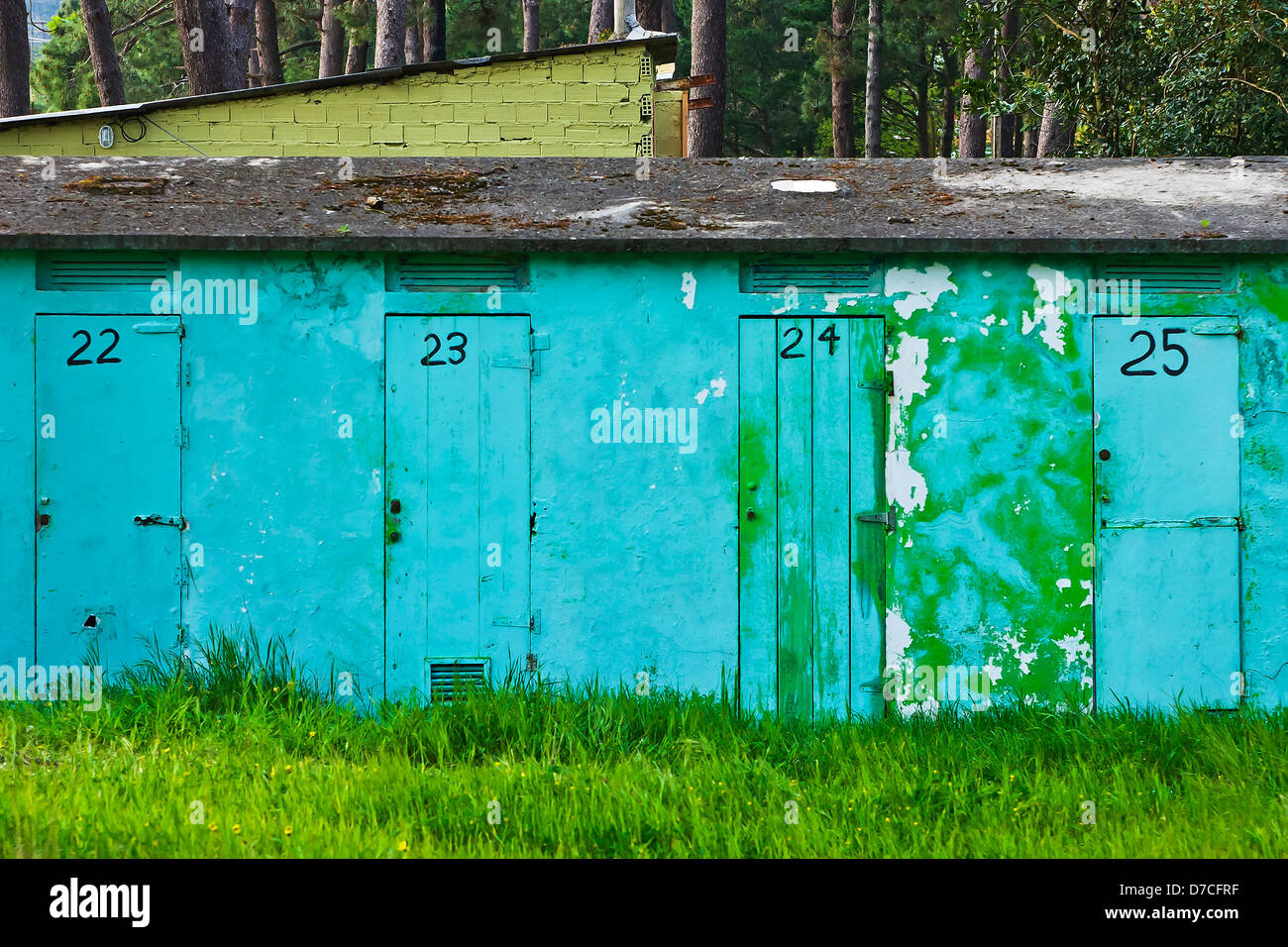 blue facade with doors numbered and forest in the background Stock Photo