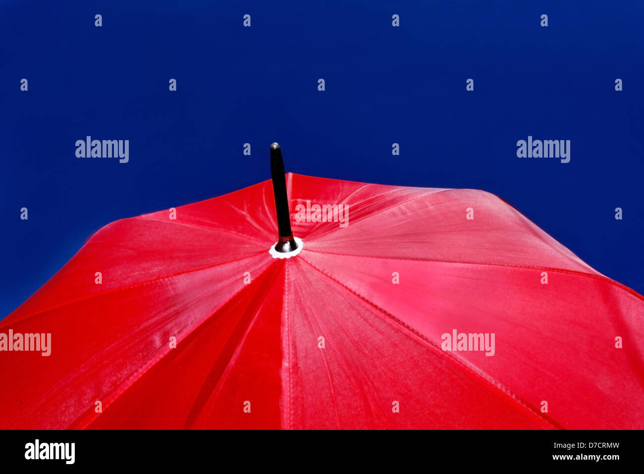 Large size red umbrella isolated in clear dark blue sky. Stock Photo
