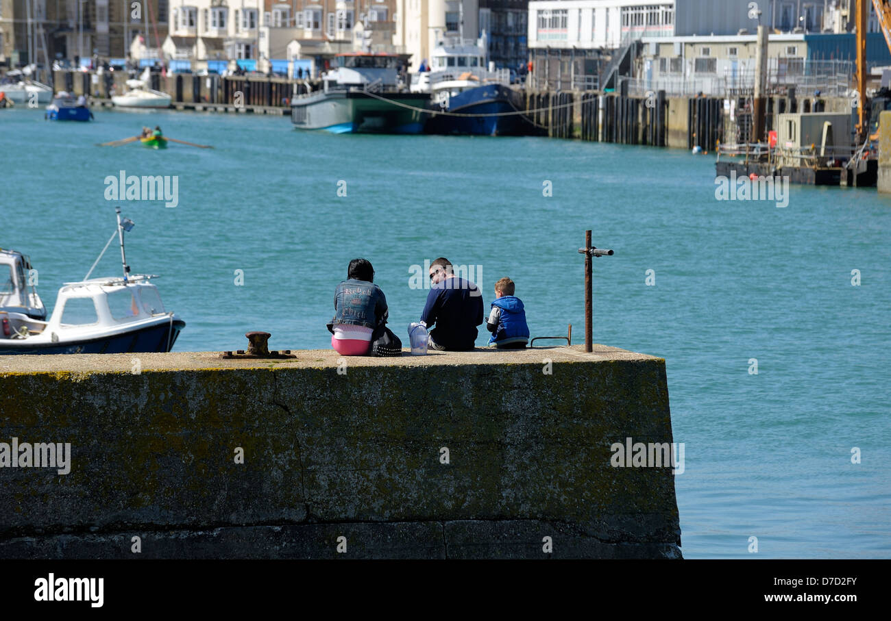 A family crab fishing on the harbour wall Weymouh Dorset ngland uk Stock Photo