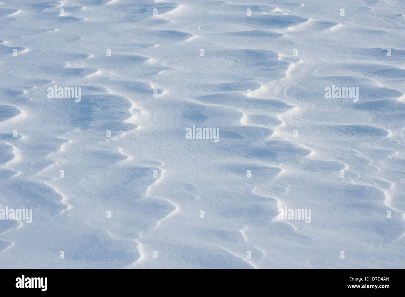 Patterns on wind-driven snow catch the sunlight on a cold winter's day. Stock Photo