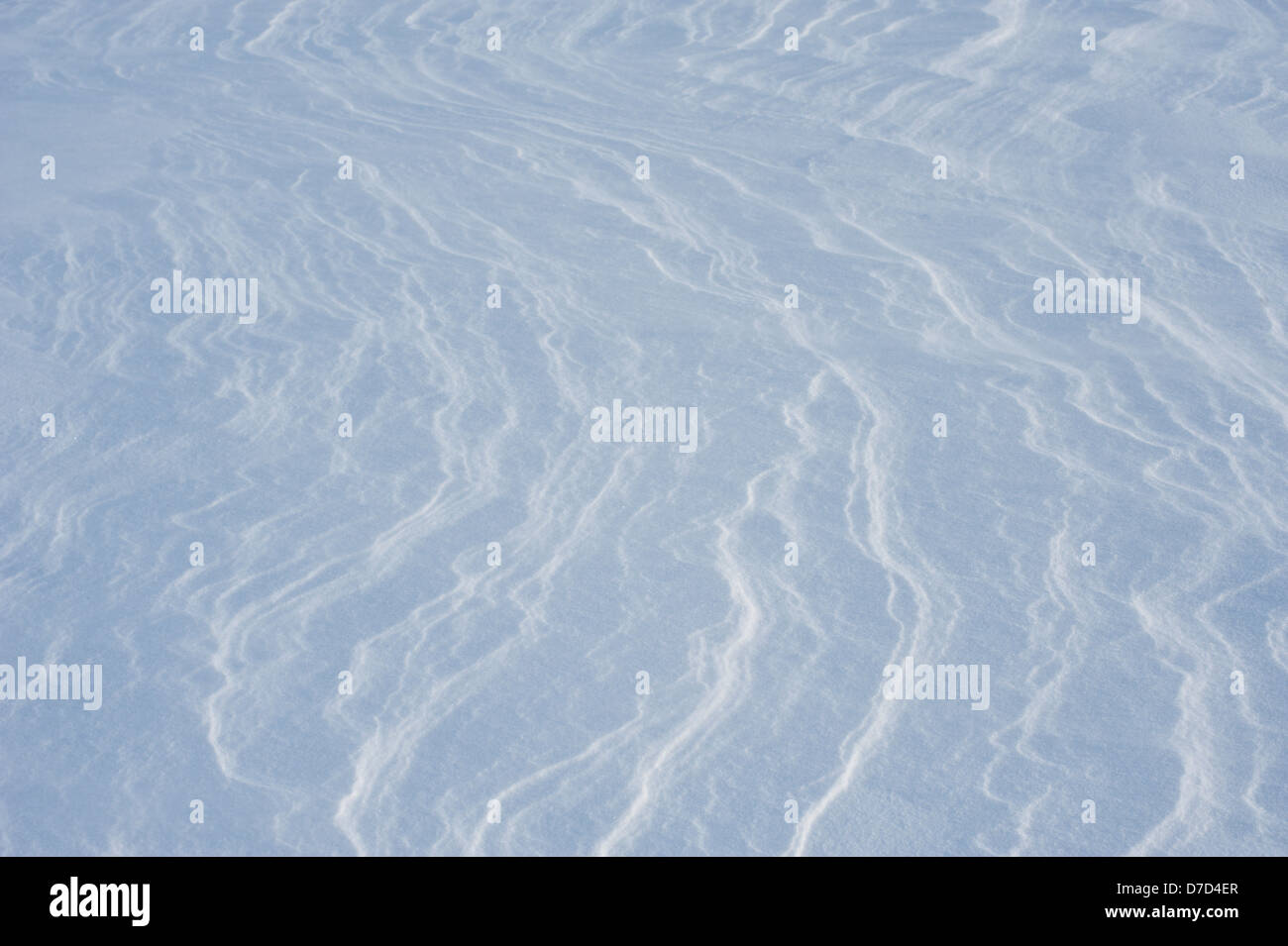 Patterns on wind-driven snow catch the sunlight on a cold winter's day. Stock Photo