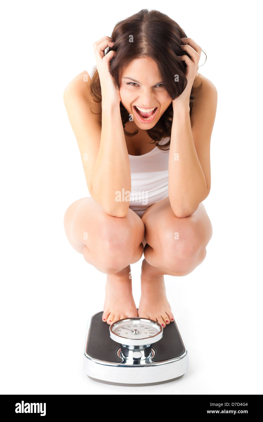 Diet and weight, young woman sitting on her haunches on a scale Stock Photo