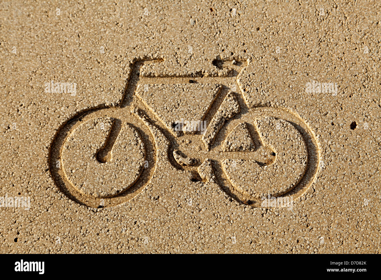Bicycle diagram engraved in a yellow stone brick, indicating the location of a bicycle lane. Stock Photo