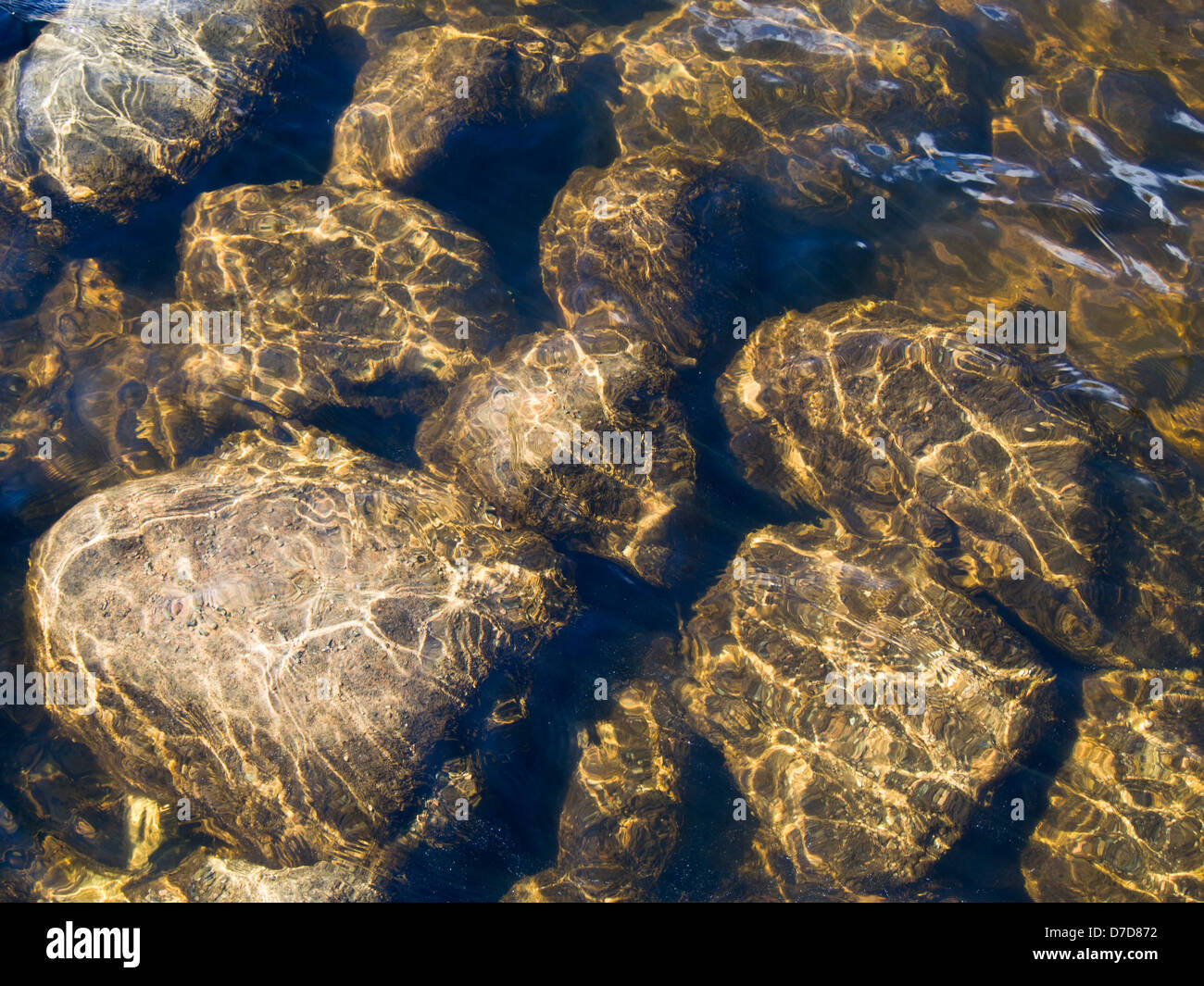 Reflected sun light through water on stones in riverbed Stock Photo