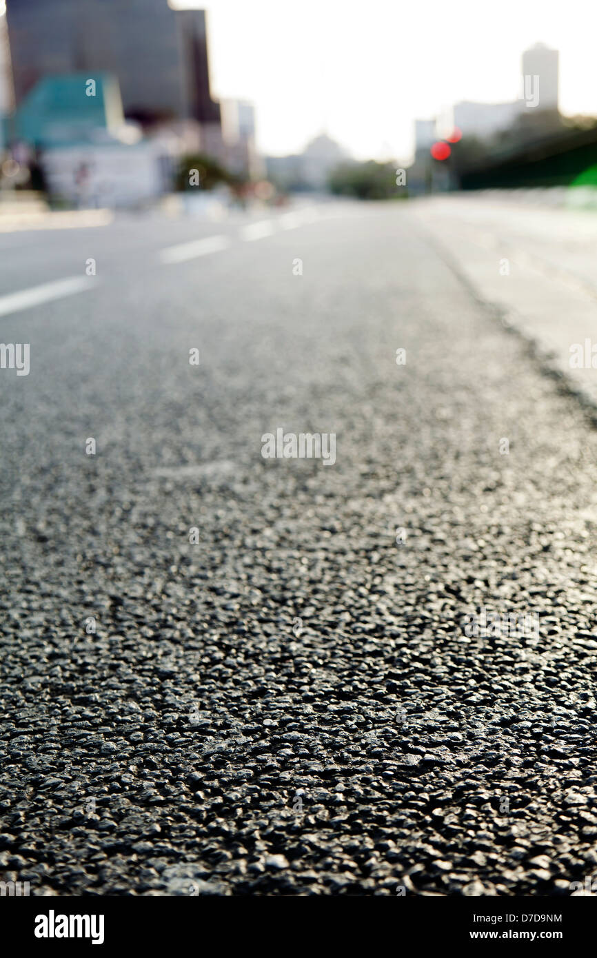 Surface level wide angle view of an empty urban road in the afternoon hours. Very shallow depth of field. Stock Photo