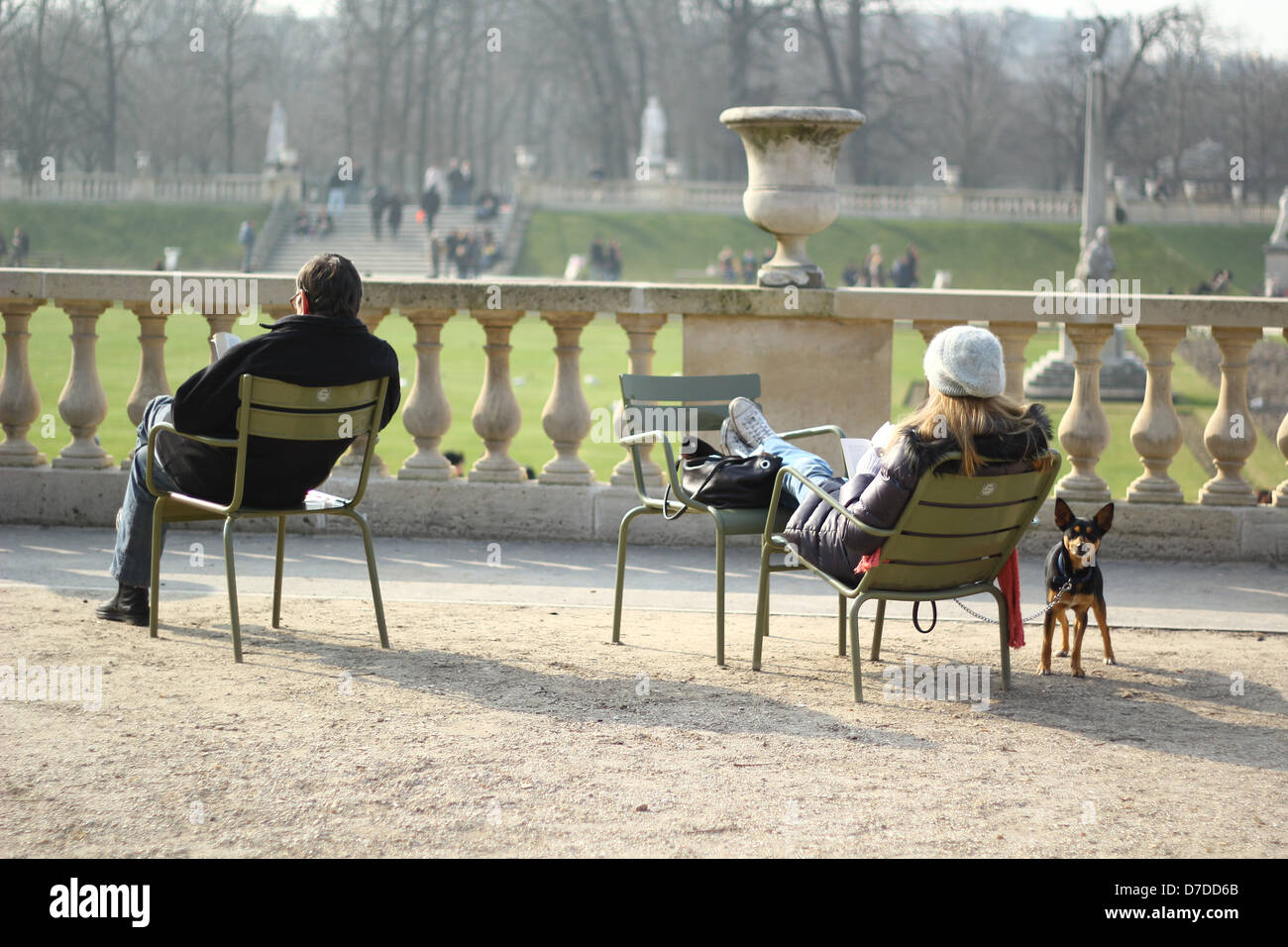 Luxembourg garden in Paris, France - people relaxing in garden chairs at early spring Stock Photo