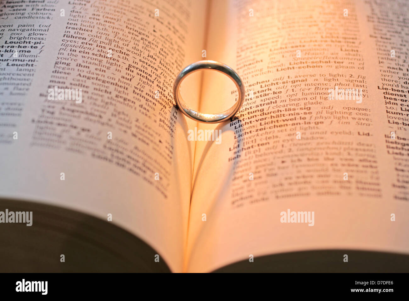 Ring on dictionary with shadow in heart shape Stock Photo