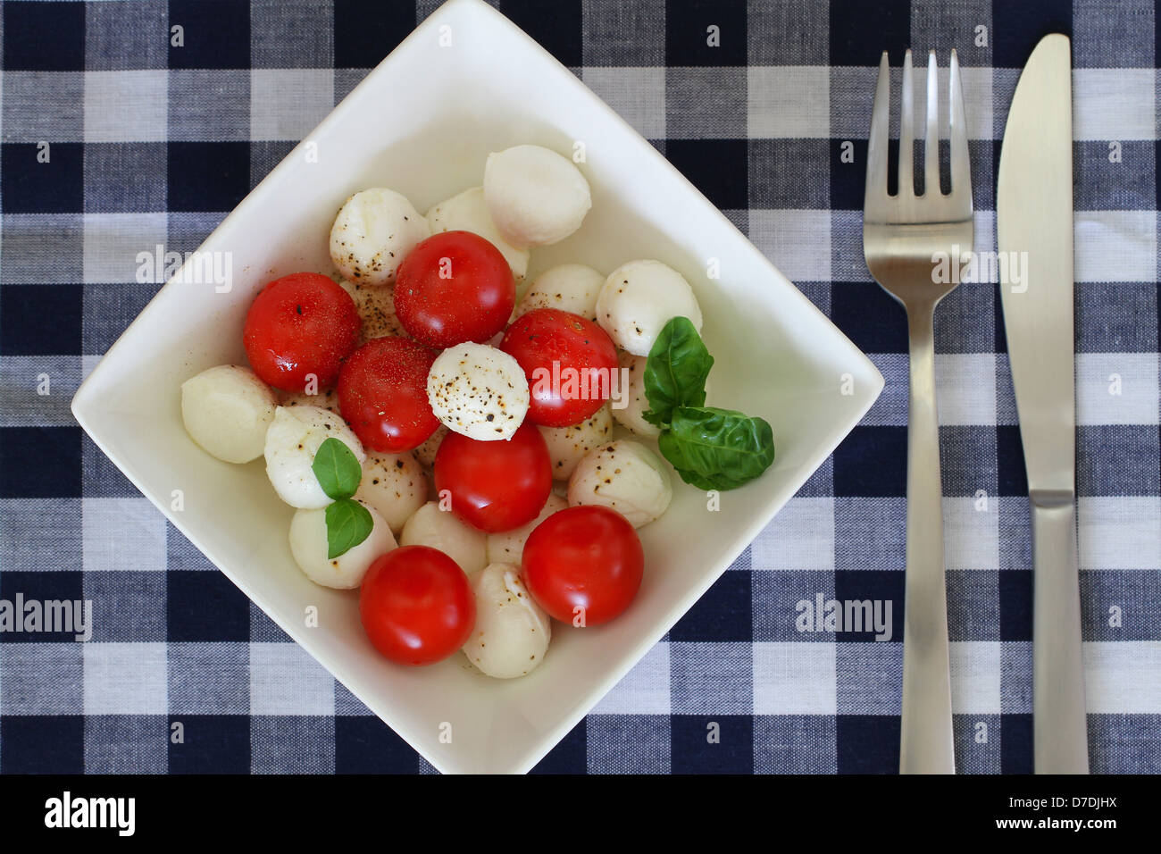 Mozzarella and cherry tomato salad with basil and black pepper Stock Photo