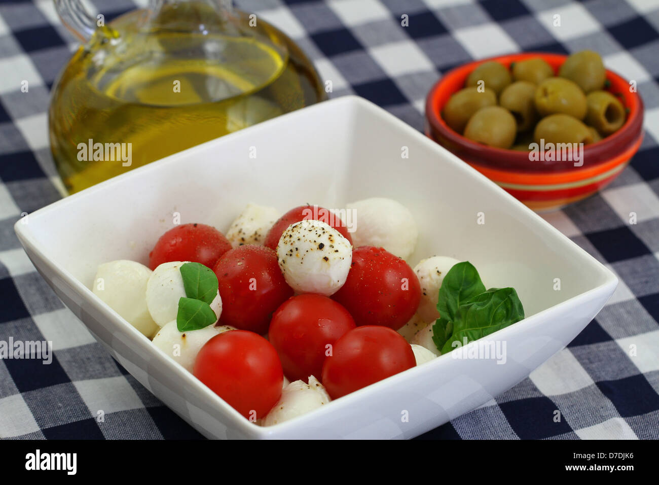 Mozzarella and cherry tomato salad, olive oil and green olives Stock Photo