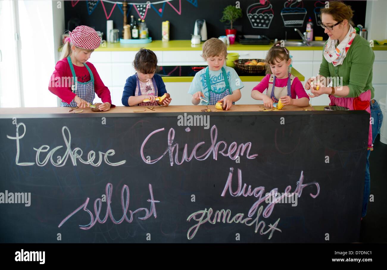 Simone Trockel (R) cooks with Angelina (8, L-R), Elda (5), Alex (6) and Laurel (5) in the 'KinderKueche' in Hanover, Germany, 24 April 2013. Children cook their favorite dishes under the motto 'Self made meals are most tasty'.  Photo: Julian Stratenschulte Stock Photo