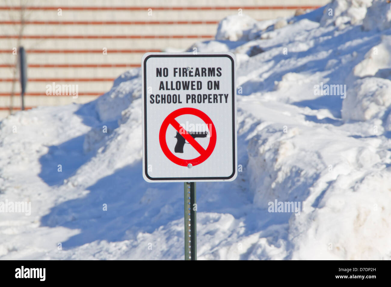 No Firearms Allowed on School Property Sign outside a school in the snow. Stock Photo