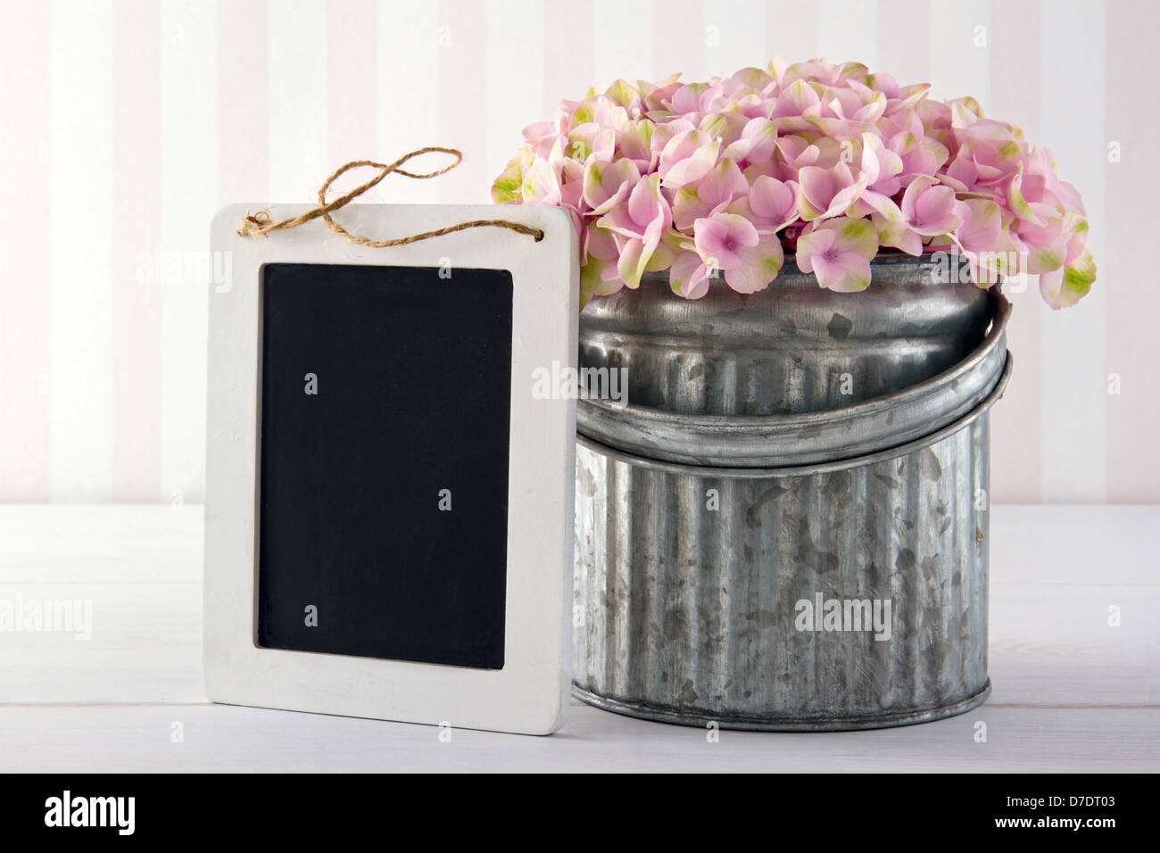 Pink hydrangea flowers in a metal vase on vintage background with empty