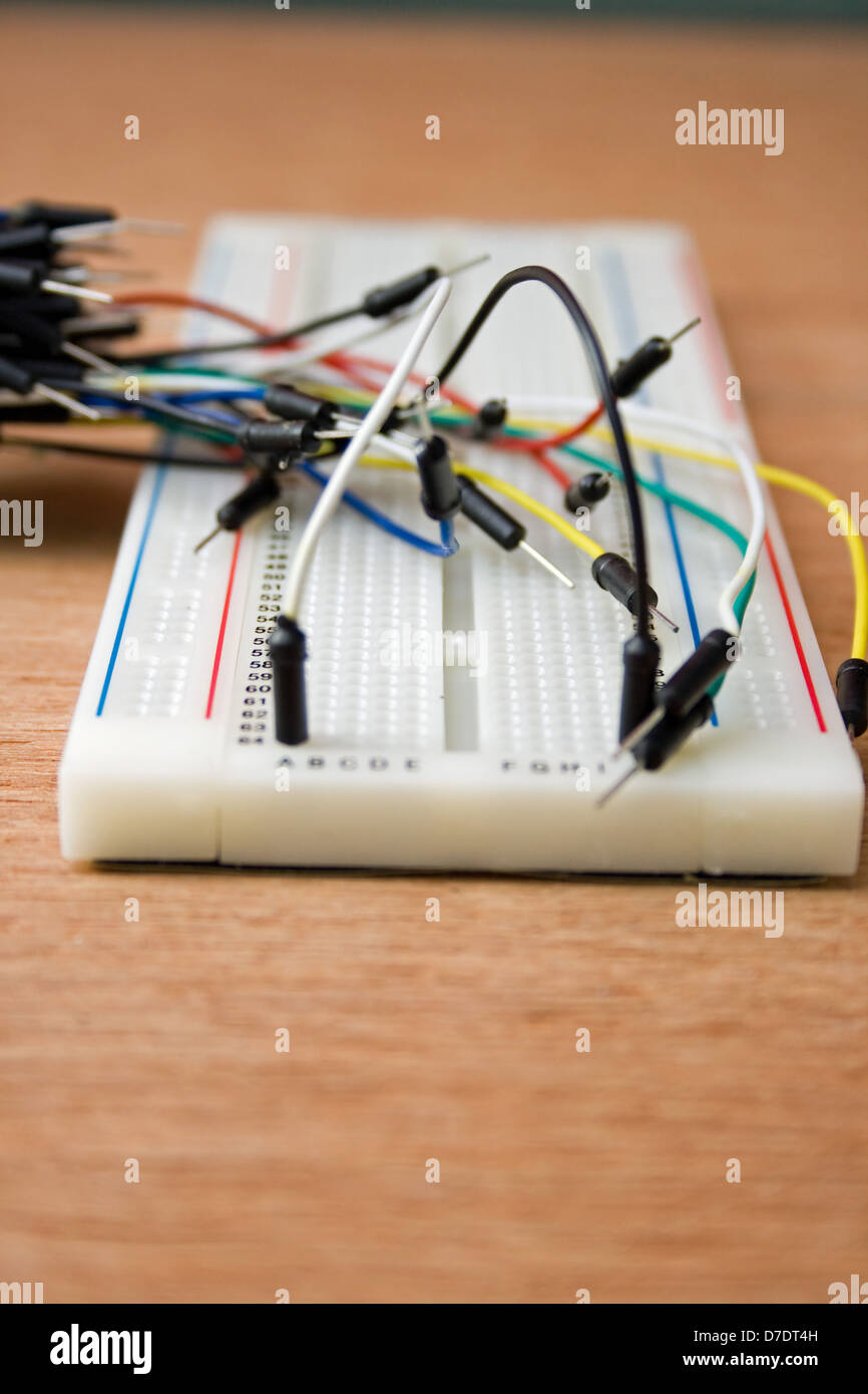 Solderless breadboard with jumper wires on a wooden worktop Stock