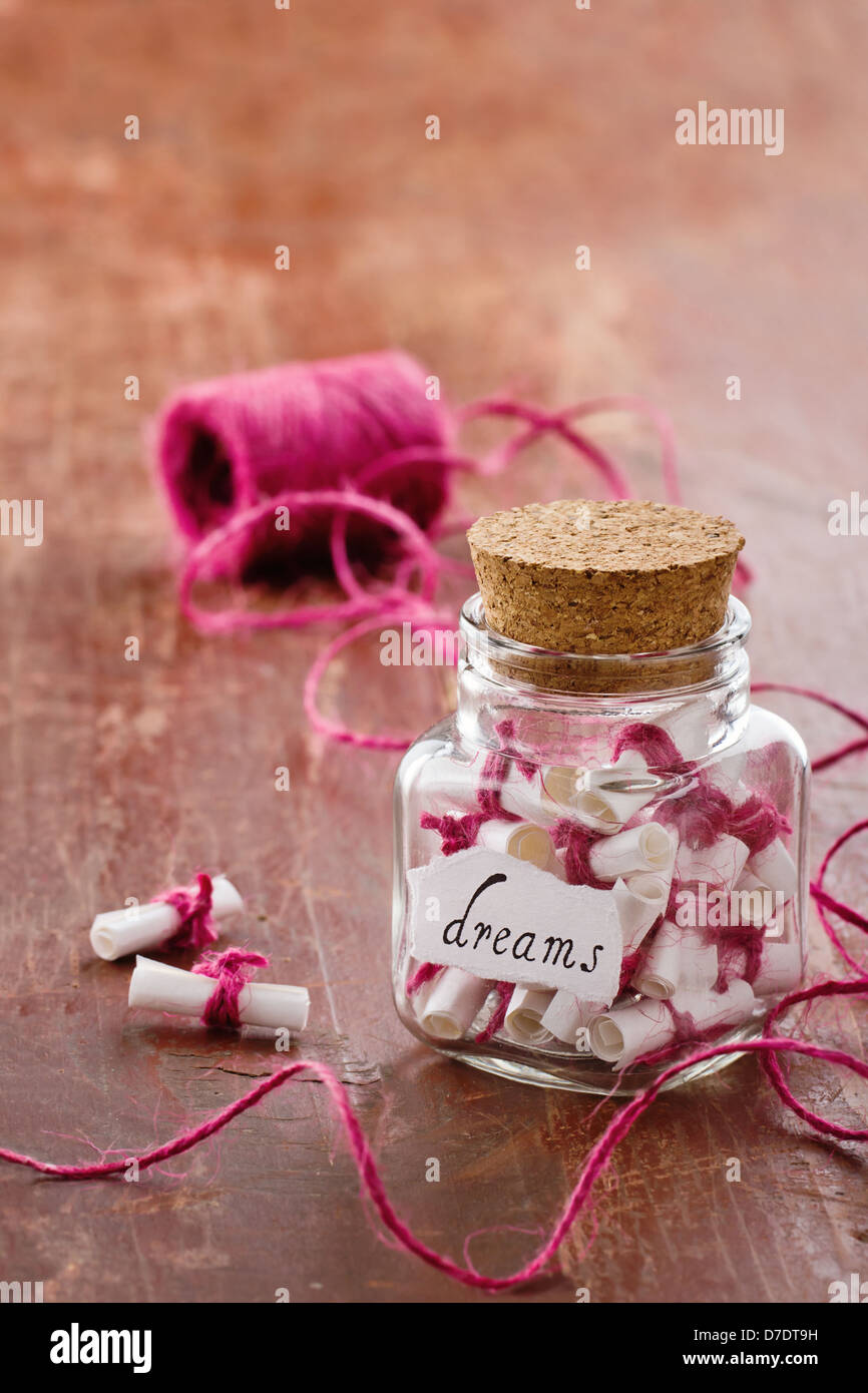 Dreams written on a white rolled paper in a glass jar on rustic vintage wooden background, dreaming optimism concept Stock Photo