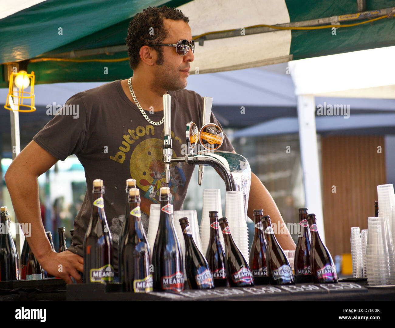 A barman pouring real ale from beer taps from Greenwich Meantime brewery stand, South Bank, London, England Stock Photo