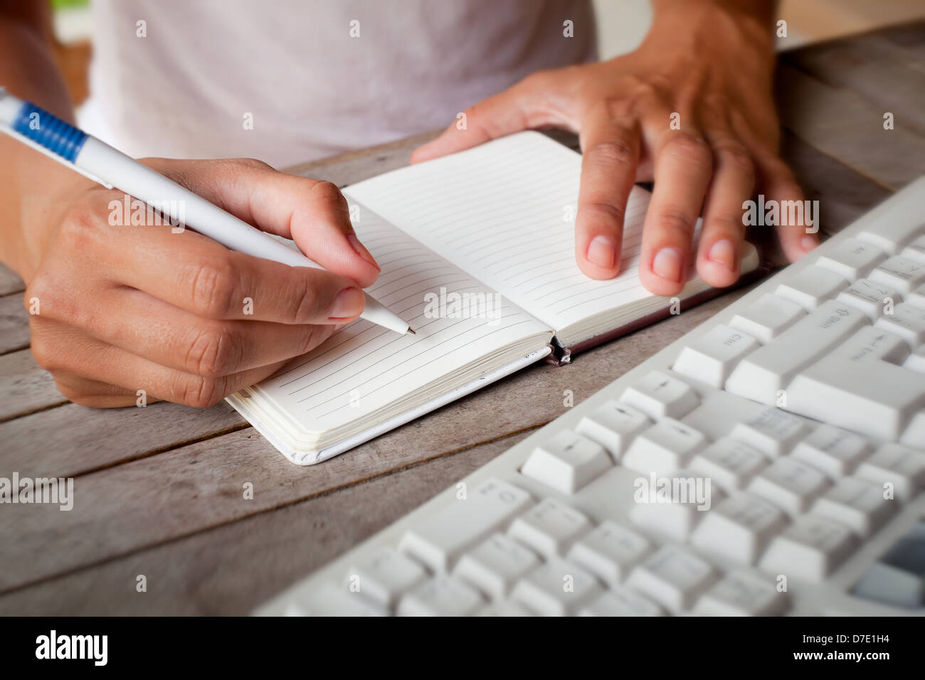 Photo of hands writes a pen in a notebook, computer keyboard on foreground Stock Photo