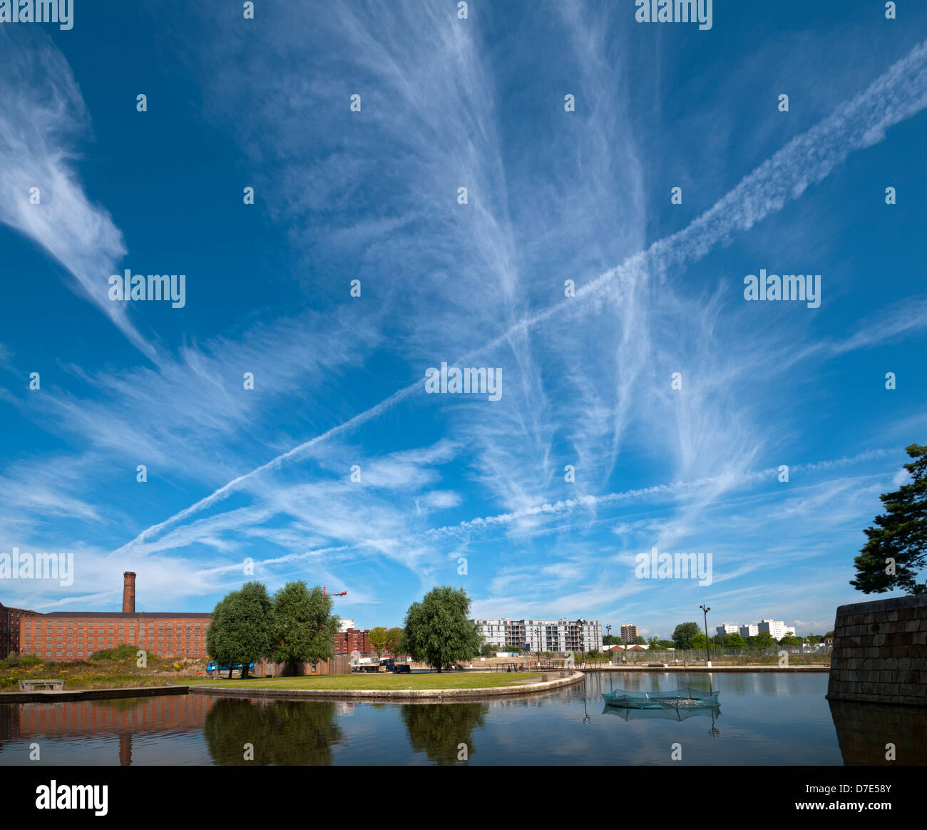 Cirrus clouds and former cotton mills reflected in the Cotton Field Park marina, New Islington, Ancoats, Manchester, England, UK Stock Photo