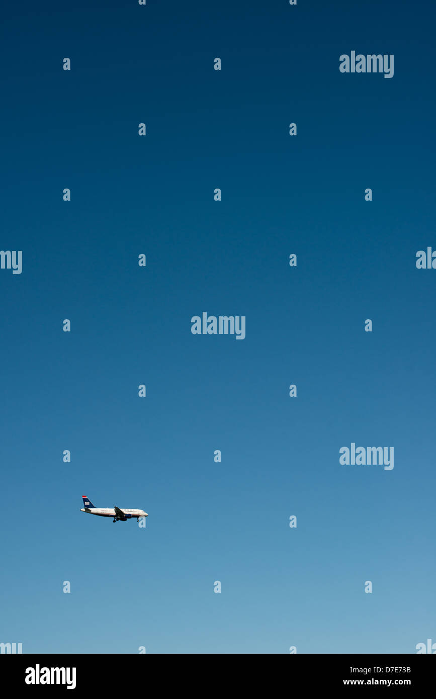 A US Airways jet comes in to land with its landing gear down, flying against a beautiful clear blue sky. Stock Photo