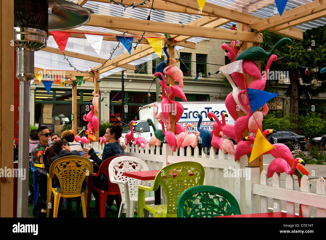 Customers seated at rustic outside covered patio pink plastic flamingos decor Rumpus Room restaurant Main Street Vancouver Stock Photo