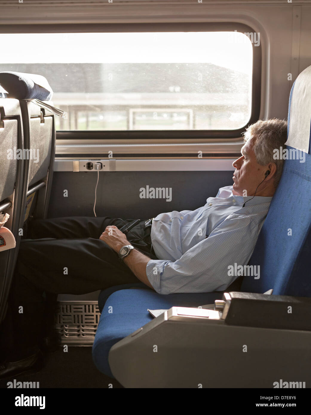 A train passenger relaxes by listening to music on the Amtrak Hiawatha. Stock Photo