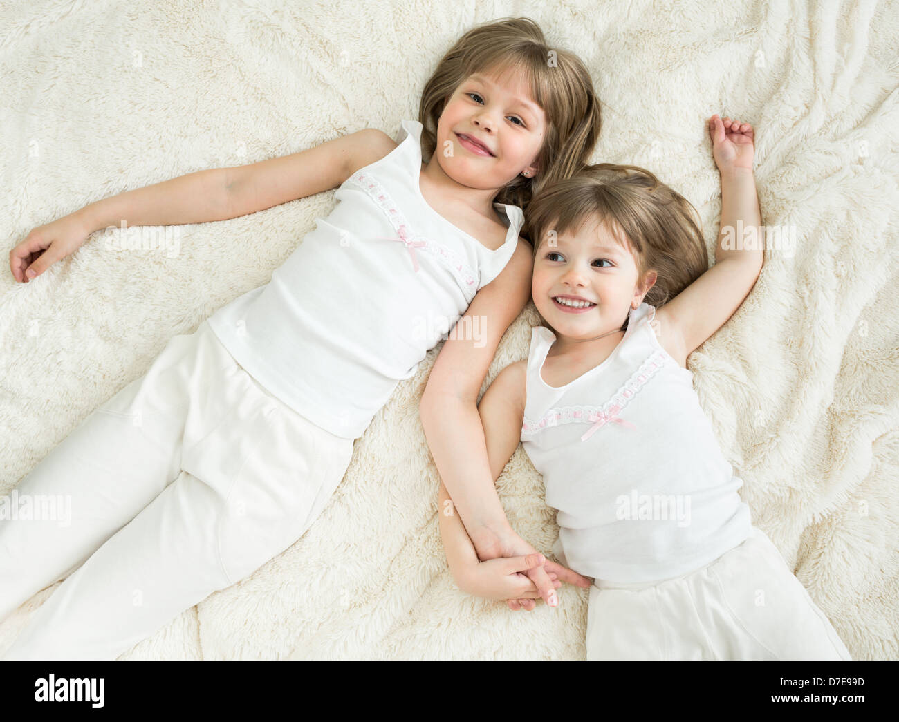 happy little sisters lying on back top view Stock Photo