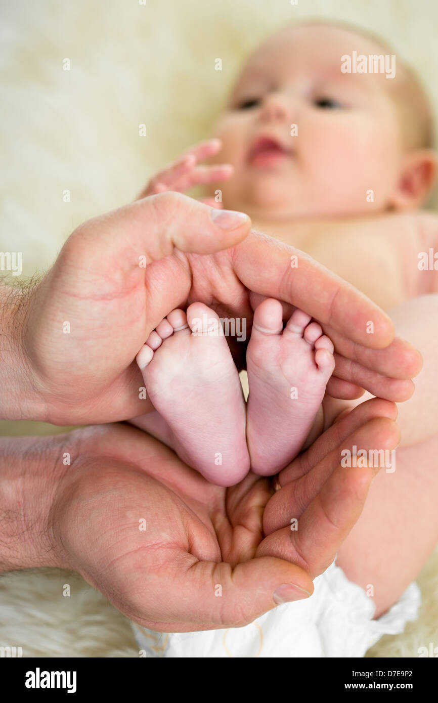 father hands holding small baby's feet Stock Photo