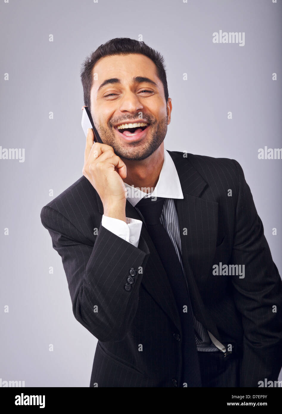 Cheerful young professional laughing while answering a phone call Stock Photo