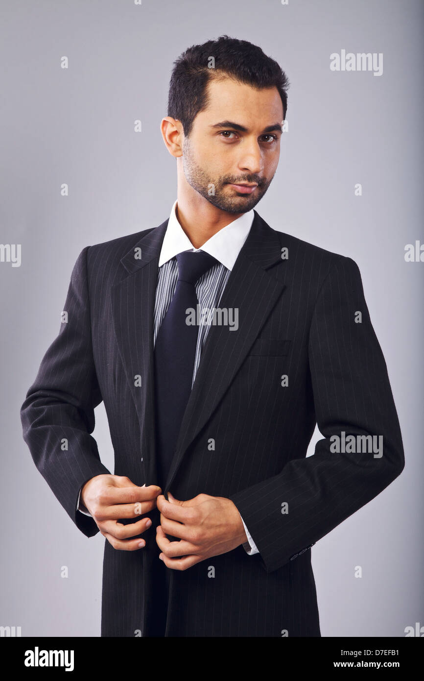 Young manager looking at you while buttoning his suit Stock Photo