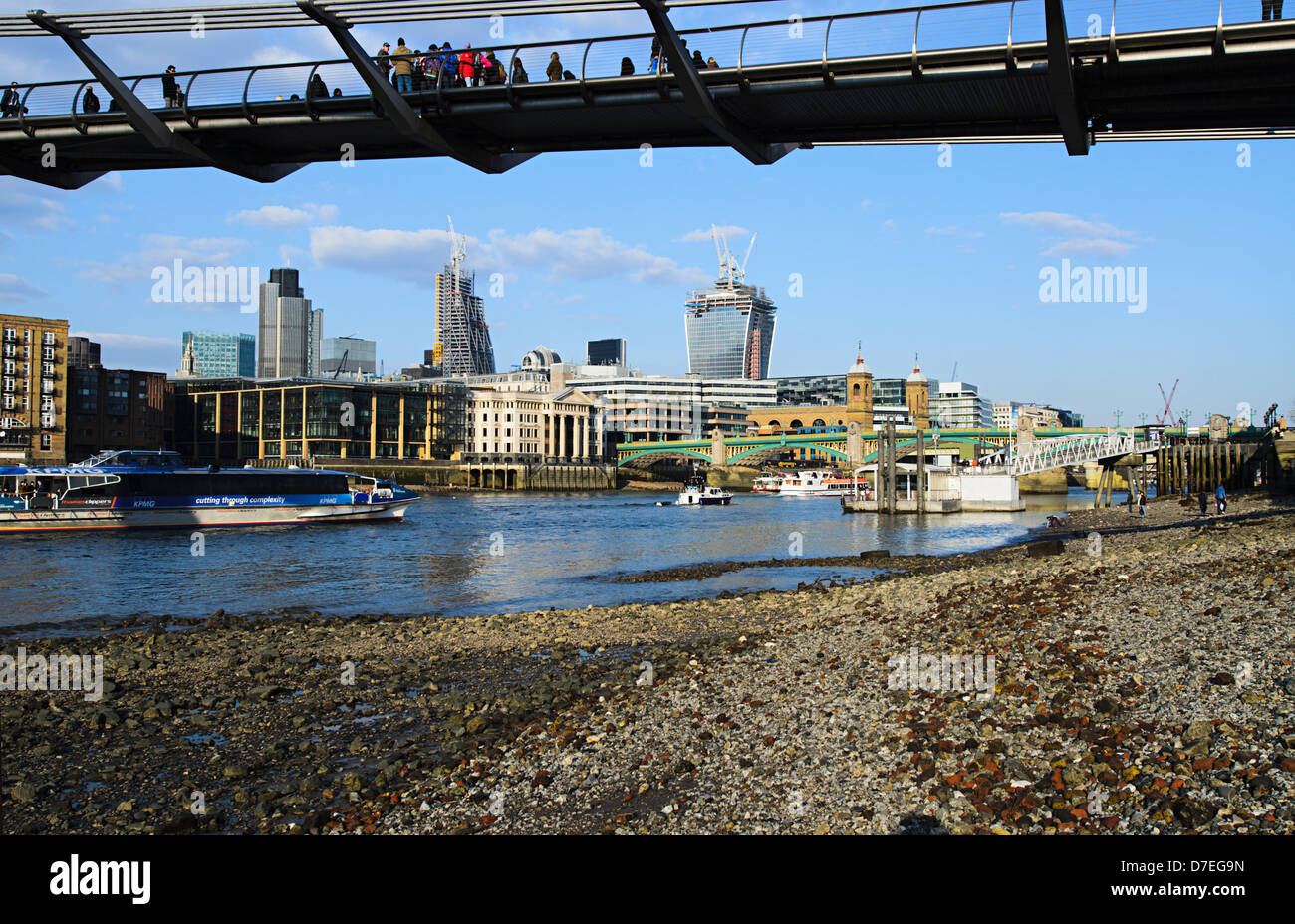 View of the City of London from the shore of the Thames,underneath the Millennium bridge at low tide Stock Photo