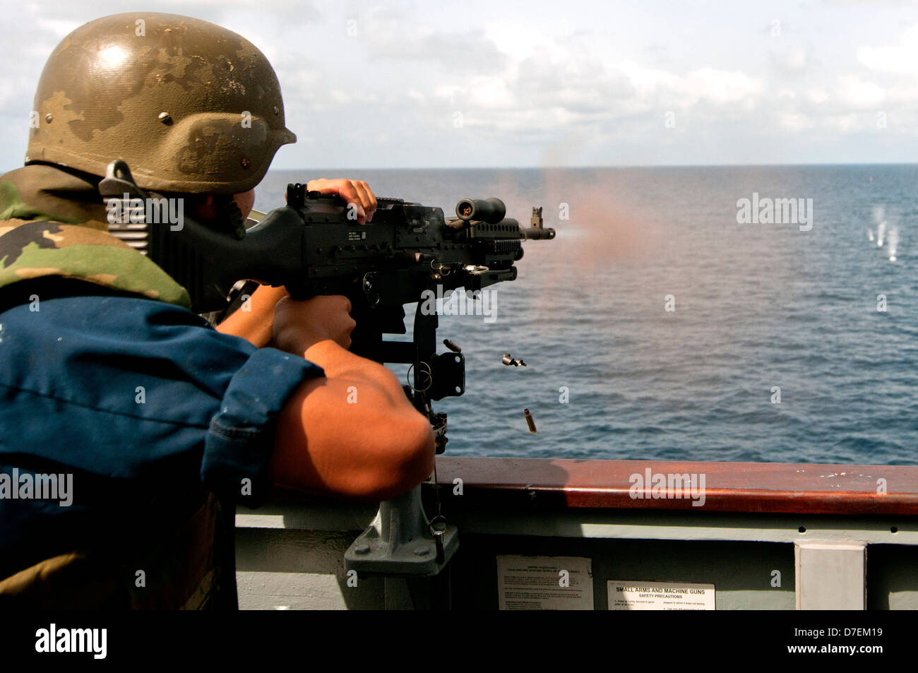 A Sailor fires an M240B machine gun at sea. Stock Photo