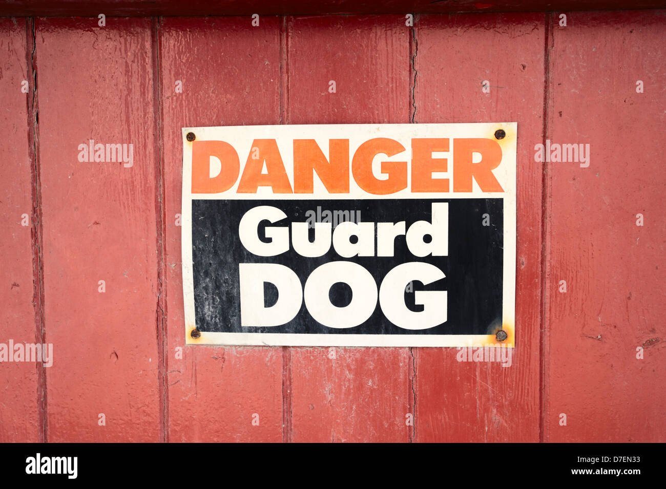 Danger Guard Dog sign on a red painted wooden gate, Wales, UK. Stock Photo