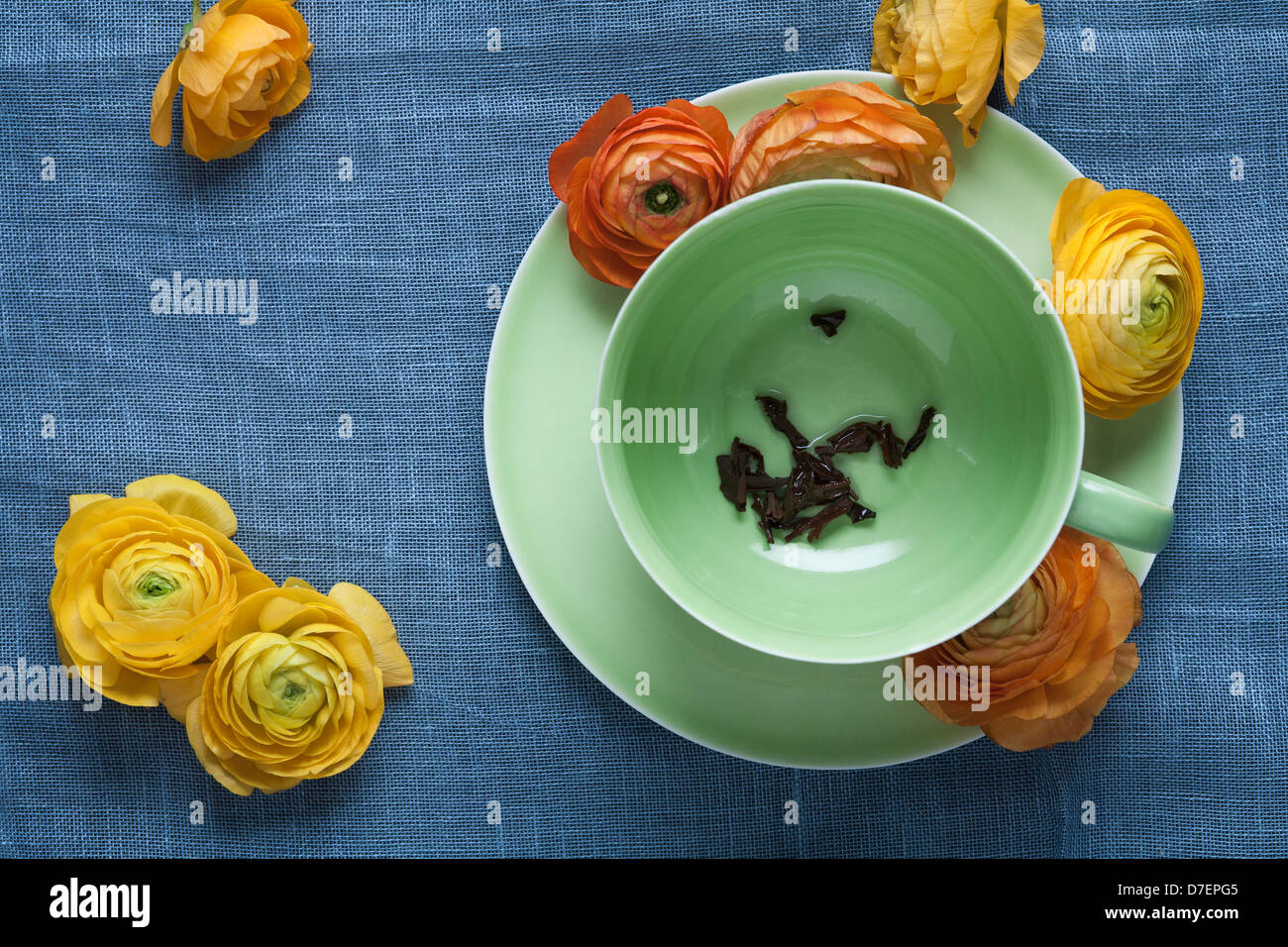 Tea leaves in empty tea cup with ranunculus flowers Stock Photo