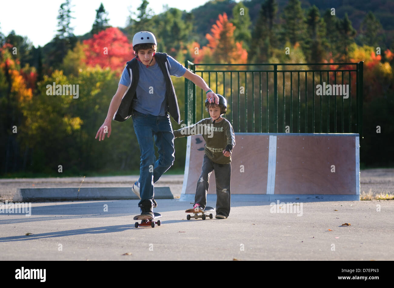 teen boy teaching younger brother to skateboard at the local outdoor skate  park on a beautiful fall evening Stock Photo - Alamy