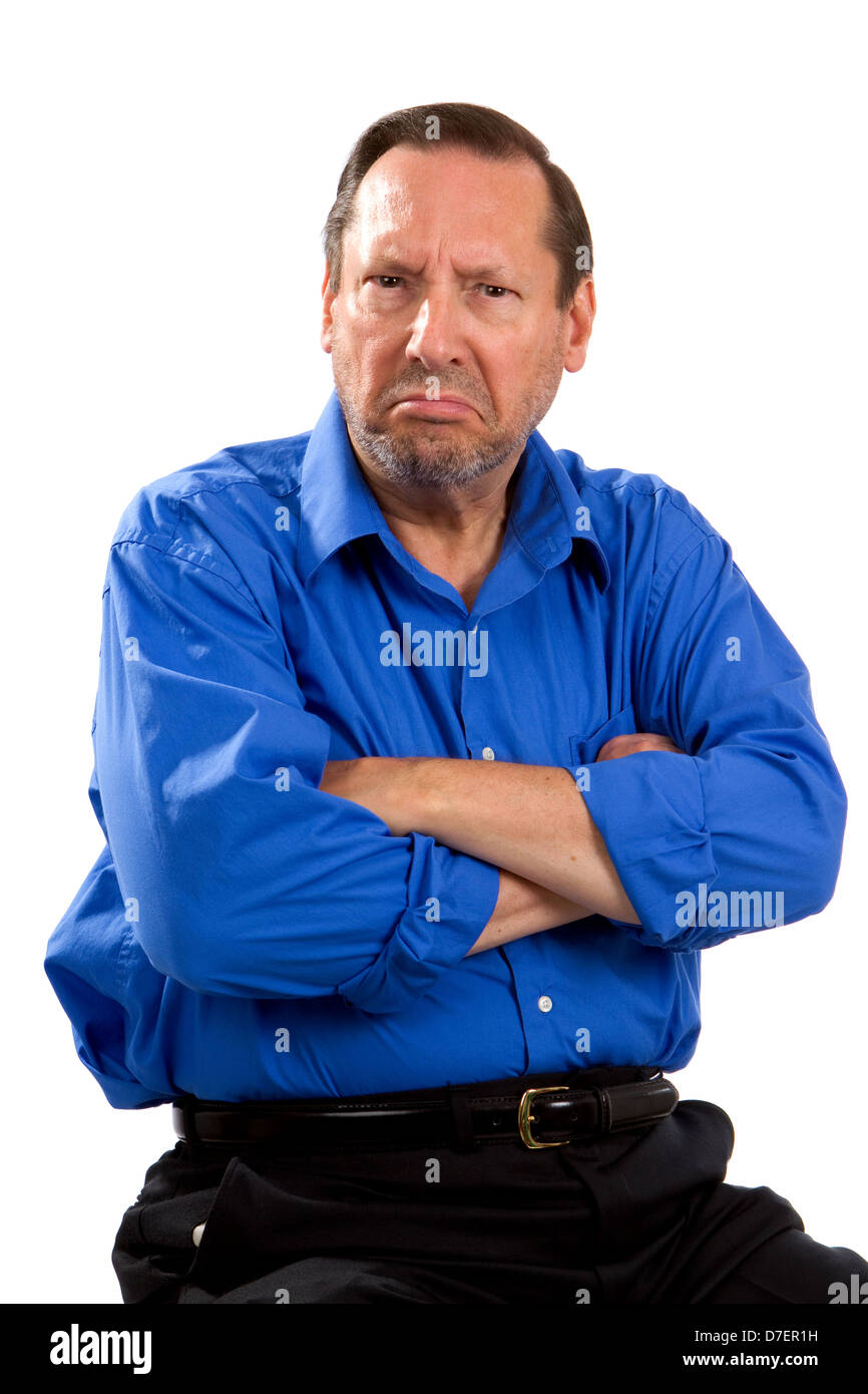 Grumpy moody senior man sits with his arms crossed and an unhappy expression on his face. Stock Photo