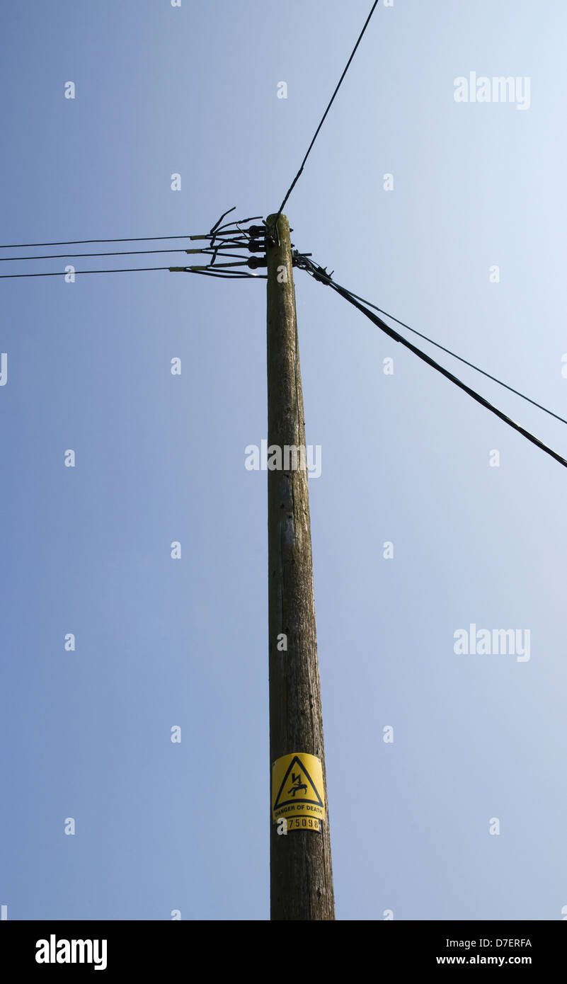 Telephone and electricity cables and post against a blue sky;England