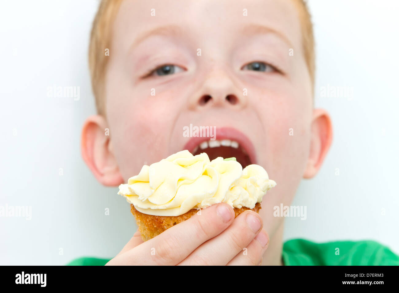 handsome little boy eating a fresh cream cup cake with messy face Stock Photo