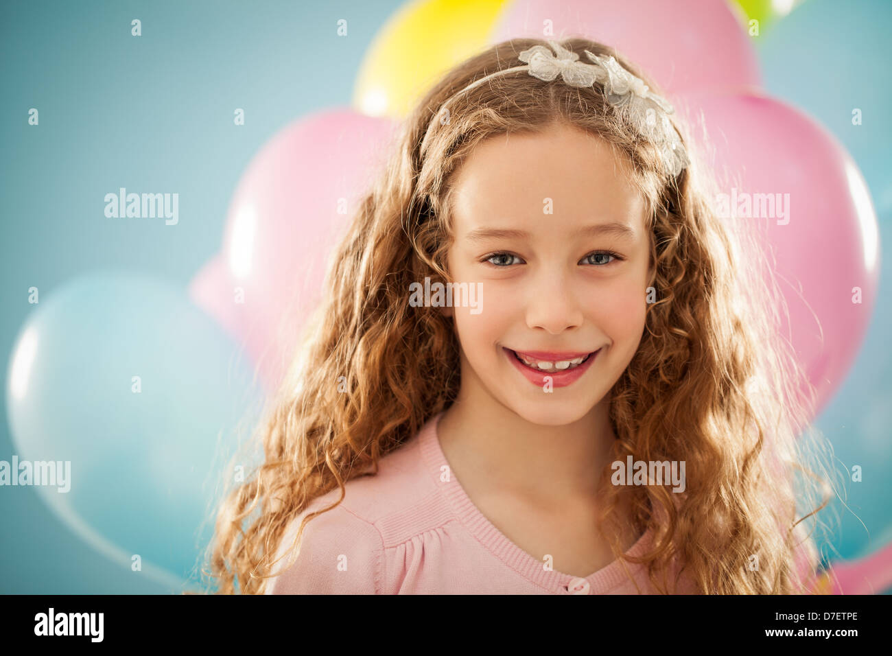 Beautiful smiling girl portrait with balloons in front of blue background. Stock Photo