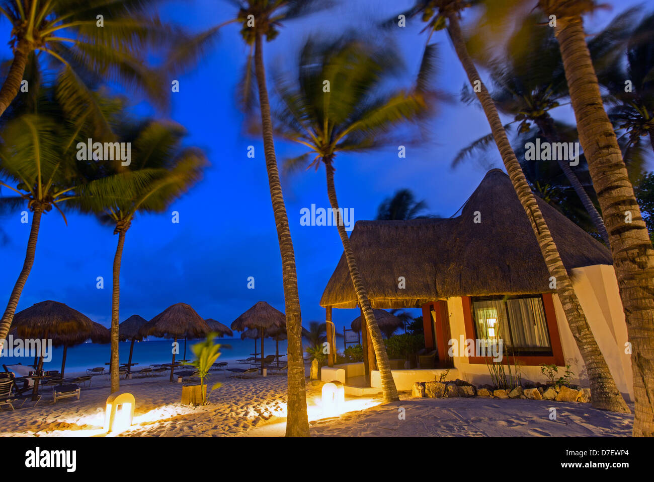 cabana style accommodation on the beach surrounded by palm trees at dawn Stock Photo